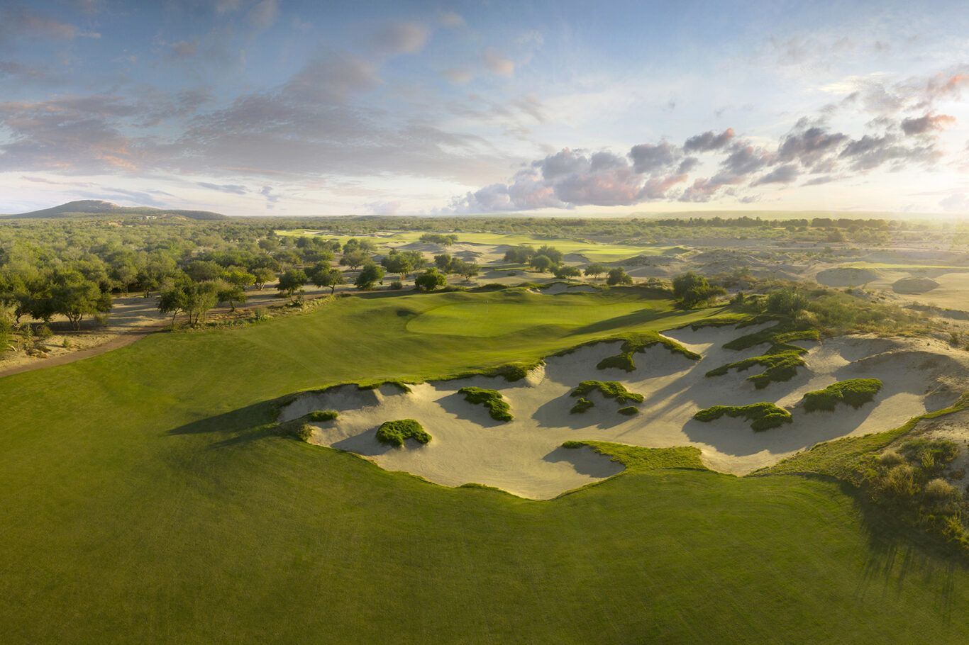 Aerial photo of the greens at the Costa Palmas Golf Course glowing at sunset